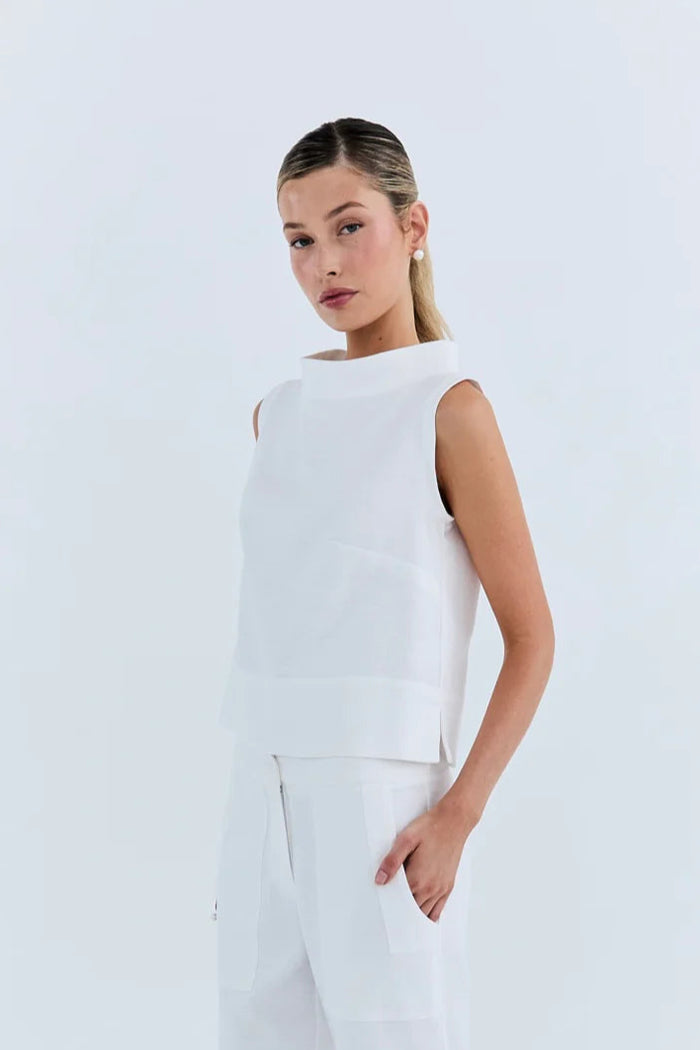 Woman wearing a white sleeveless top and pants on a light gray background